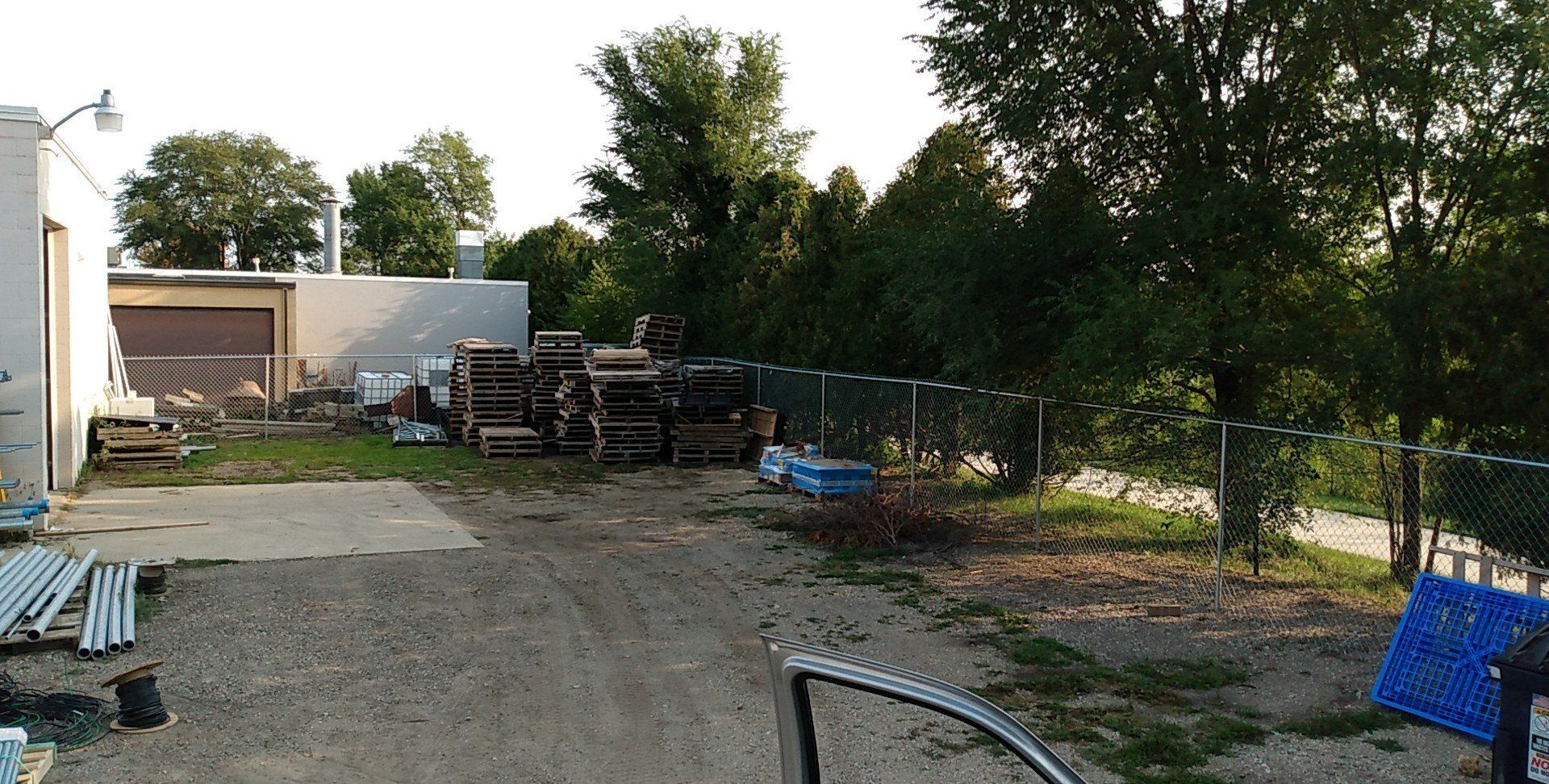 A parking lot with a chain link fence and a building in the background