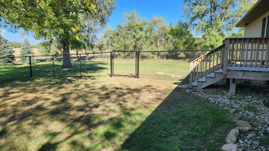 A backyard with a fence and stairs leading to a house.
