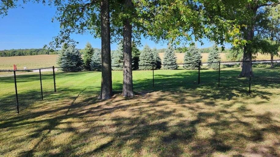 A fenced in yard with trees and a fence in the background.