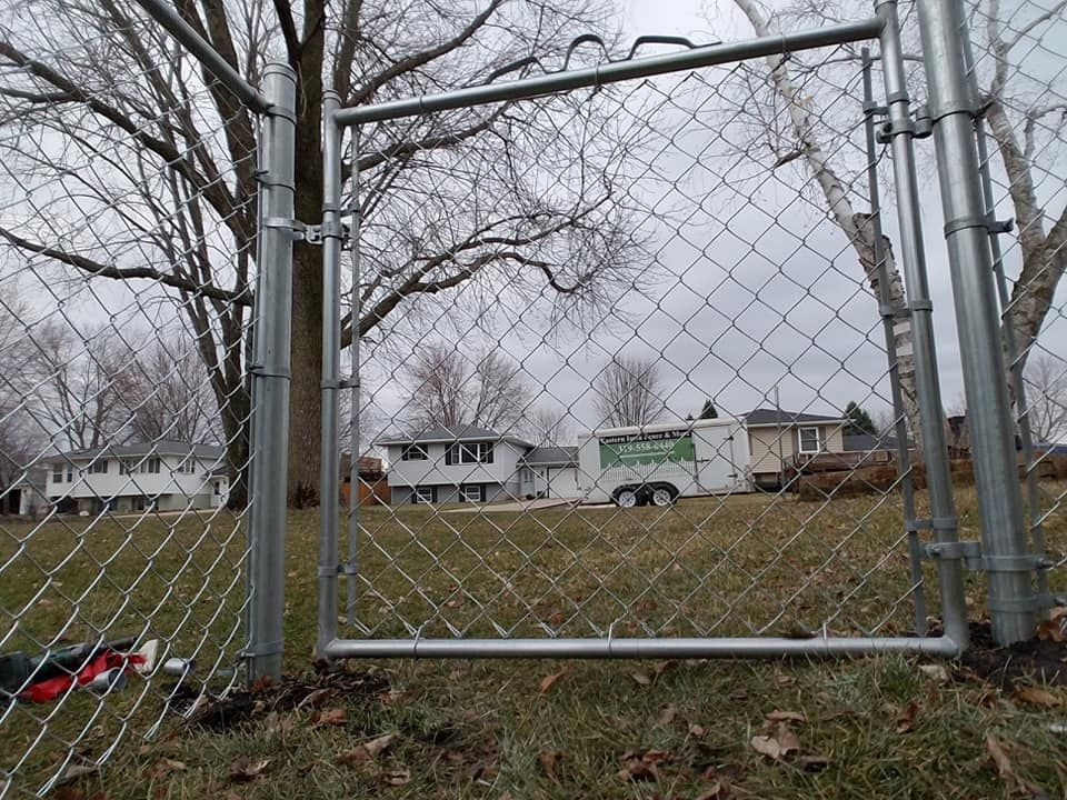 A chain link fence with a gate in the middle of a field.