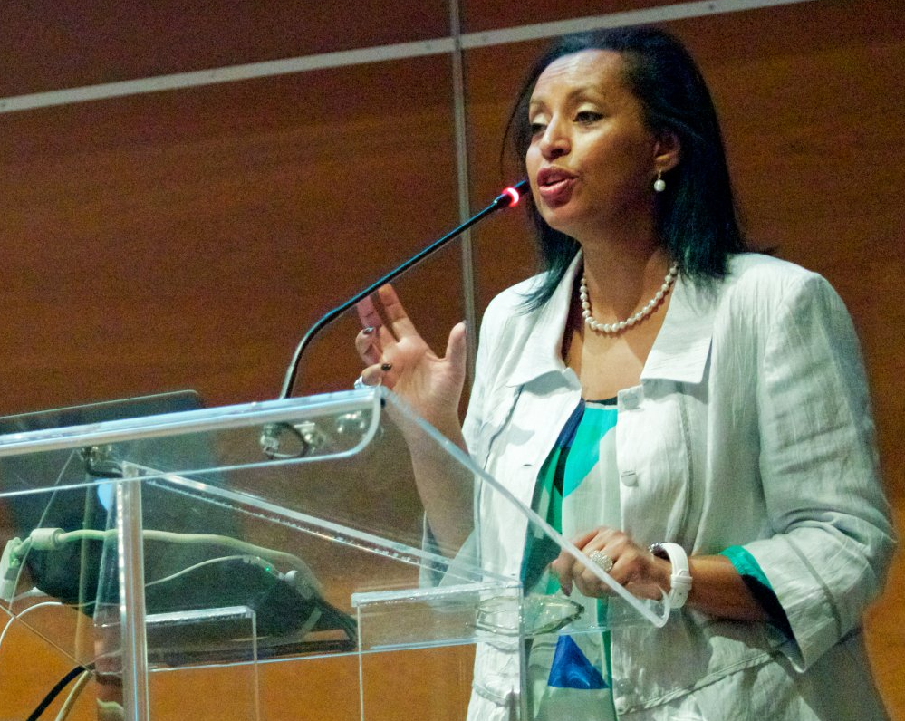 Saba Imru-Mathieu is speaking into a microphone at a podium