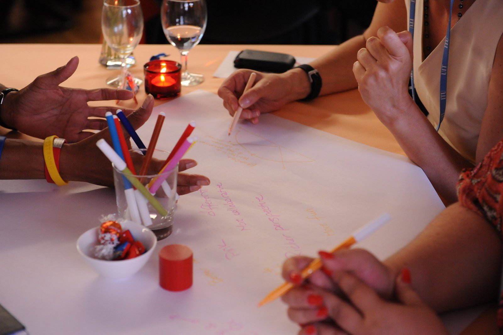 A group of people are sitting at a table with markers and candles