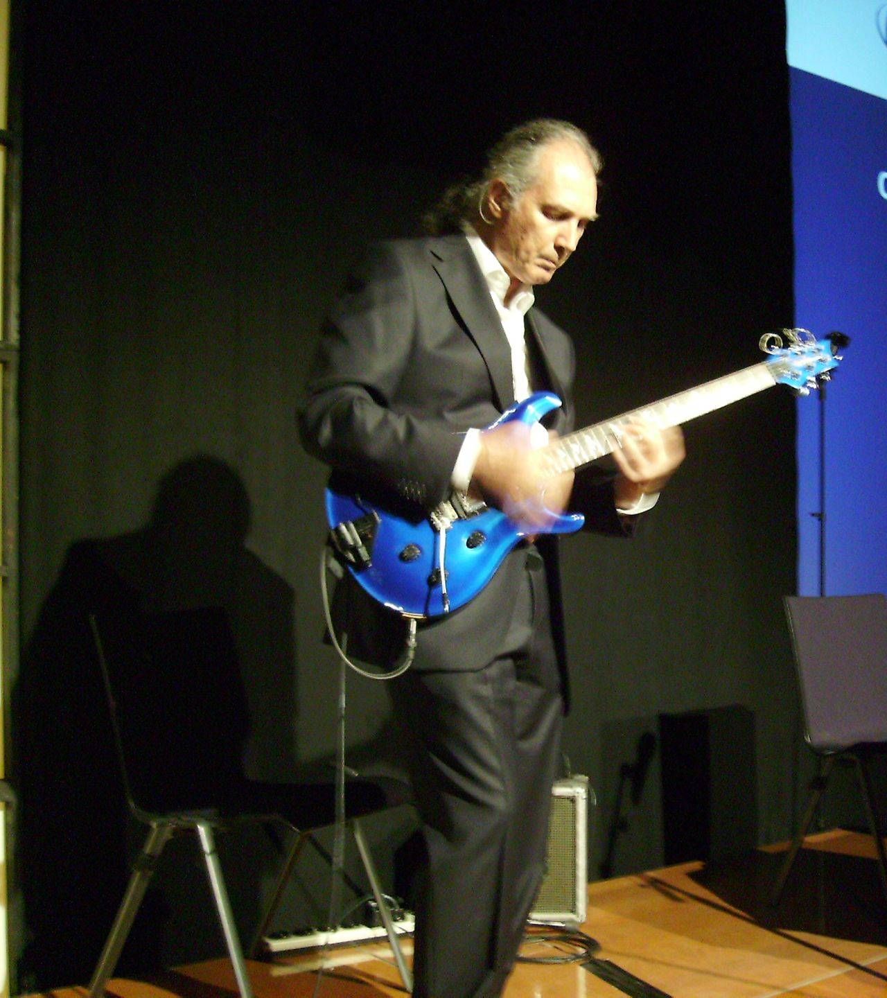 Jean Francois Mathieu, COO of Leaders Today, composer and listening specialist, in a suit is playing his blue guitar