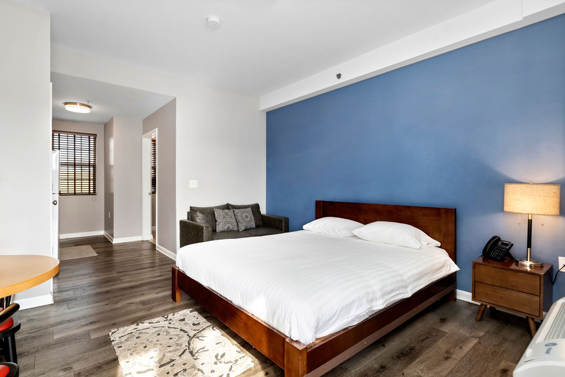 a hotel room with a king size bed , table and chairs .