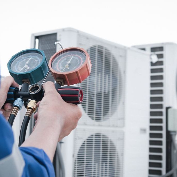 A person is holding two gauges in front of a building.