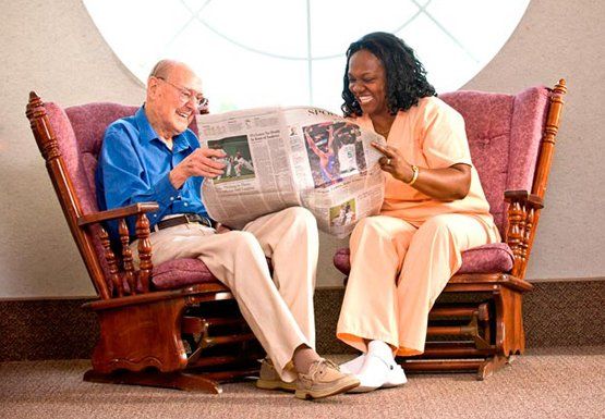 Home Companions — Woman And Senior Citizen Reading News Paper In Spring, MD