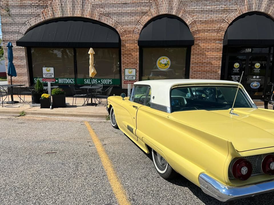 A yellow car is parked in front of a building.