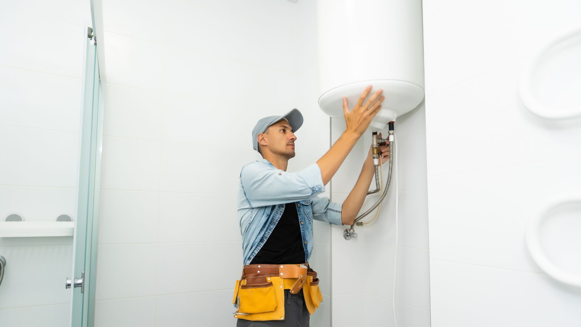 A man is fixing a water heater in a bathroom.