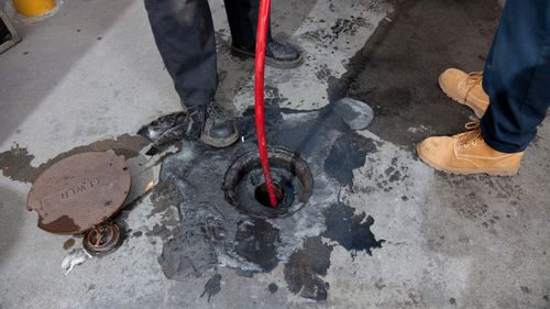 A manhole cover is being cleaned with a hose.