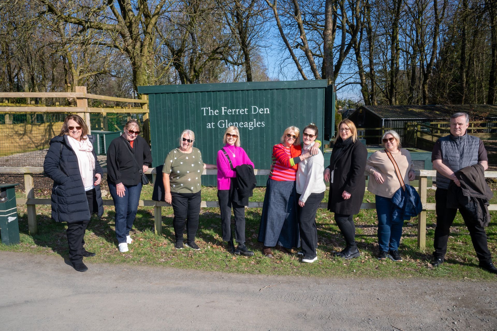 Group of people stand in front of a green sign that reads