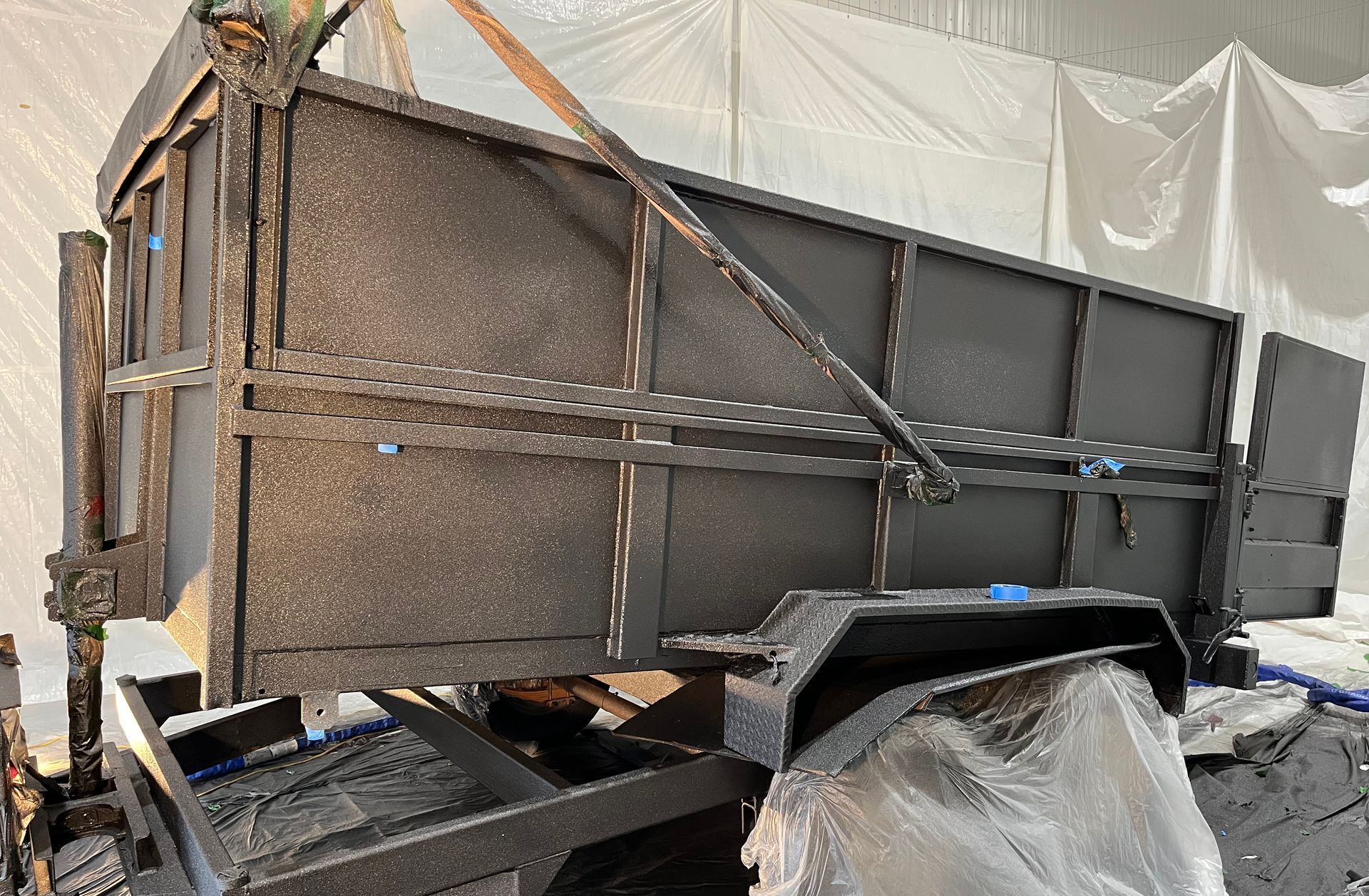 Remorque utilitaire noire avec plateau surélevé, dans un espace de rangement.