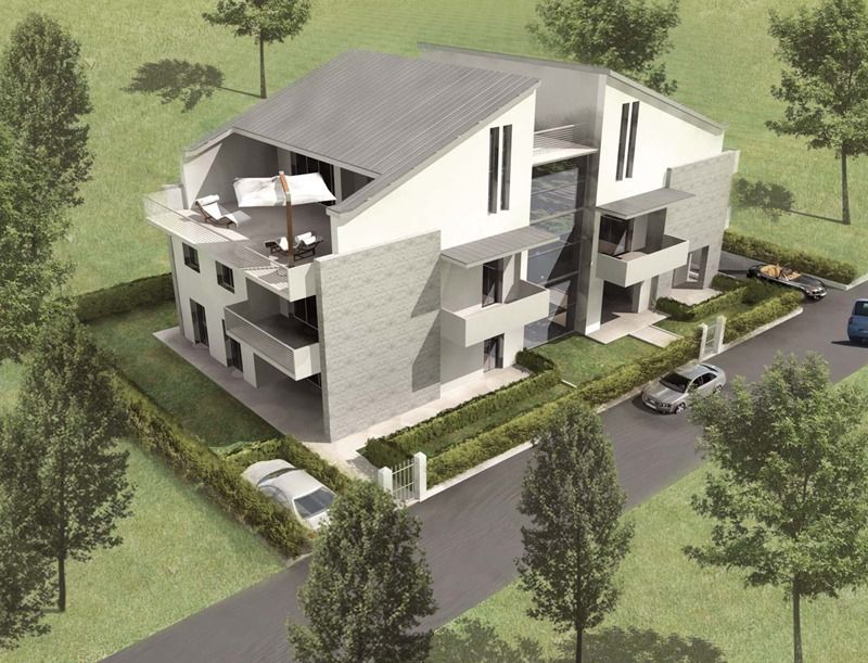 Moderno edificio multifamiliare con esterni grigi e bianchi, balconi e patio sul tetto, circondato da alberi ed erba.