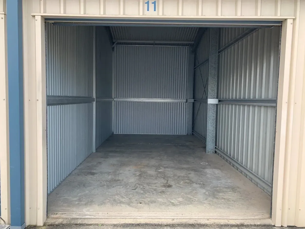 Open storage unit with blue door, beige walls, and light fixture under a blue roof, under a blue sky— Blue Ridge Self Storage In Paget, QLD