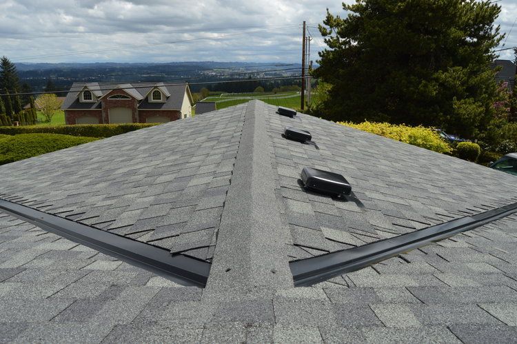 The roof of a house with a view of a city and trees.