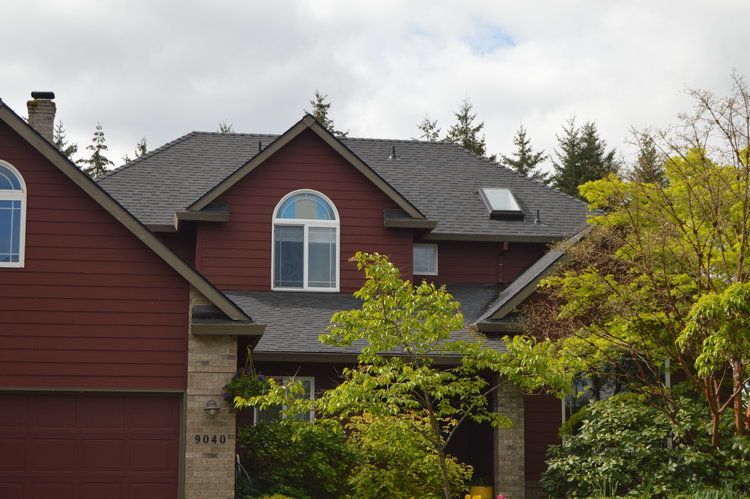 A red house with a black roof and arched windows