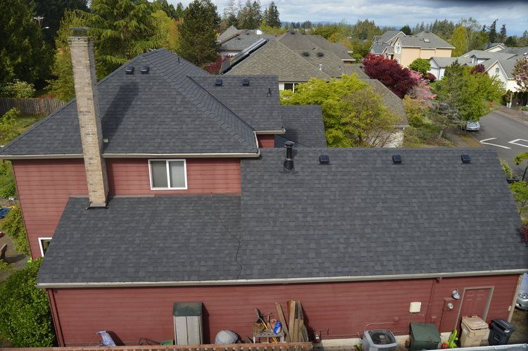An aerial view of a house with a black roof and a chimney.