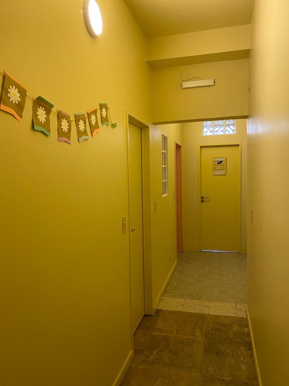 Pasillo amarillo con puertas, adornos y una lámpara.