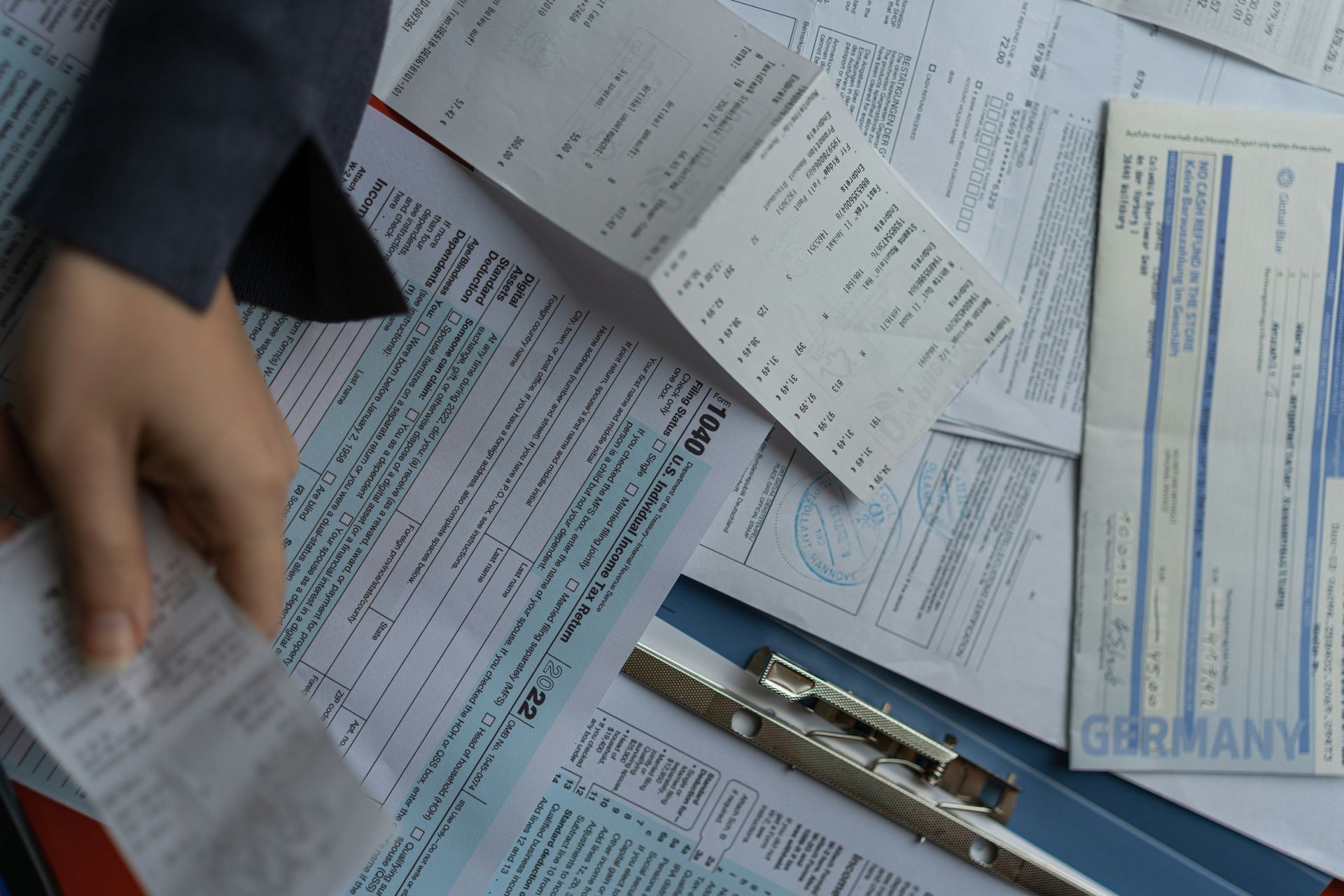 Hands sorting through a pile of paperwork and forms on a desk.