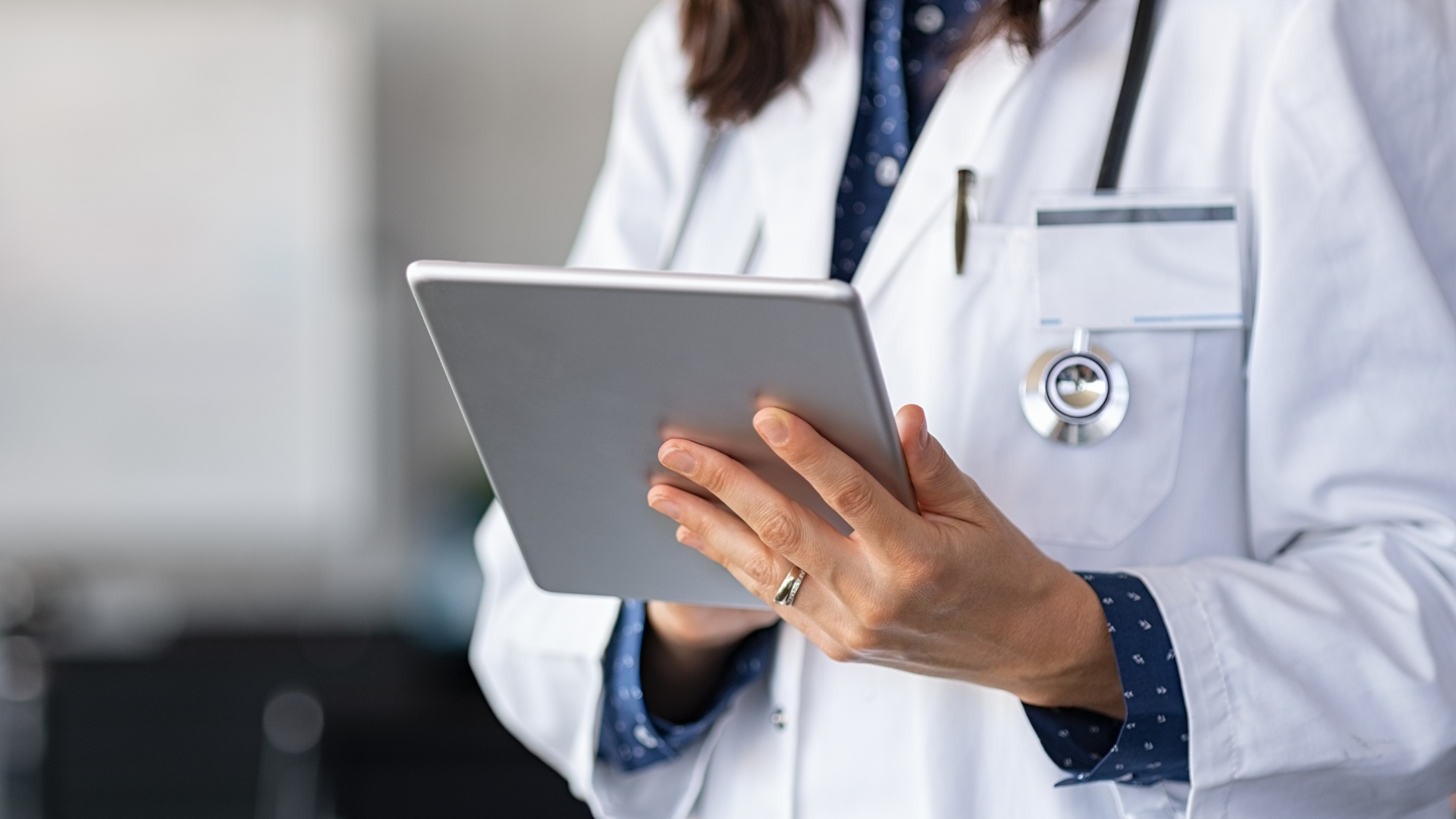 A female doctor is holding a tablet in her hands.