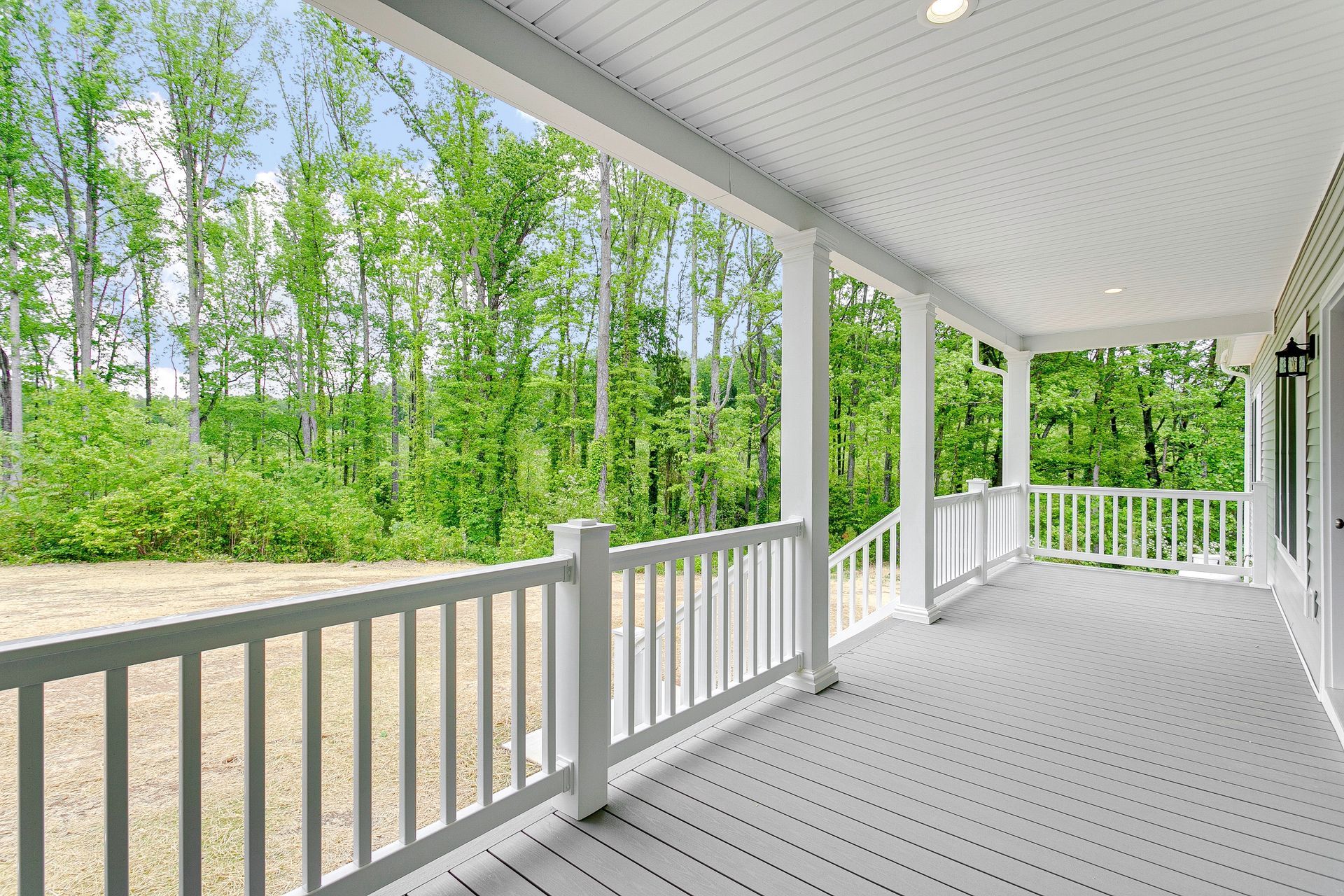 A porch with a white railing and trees in the background