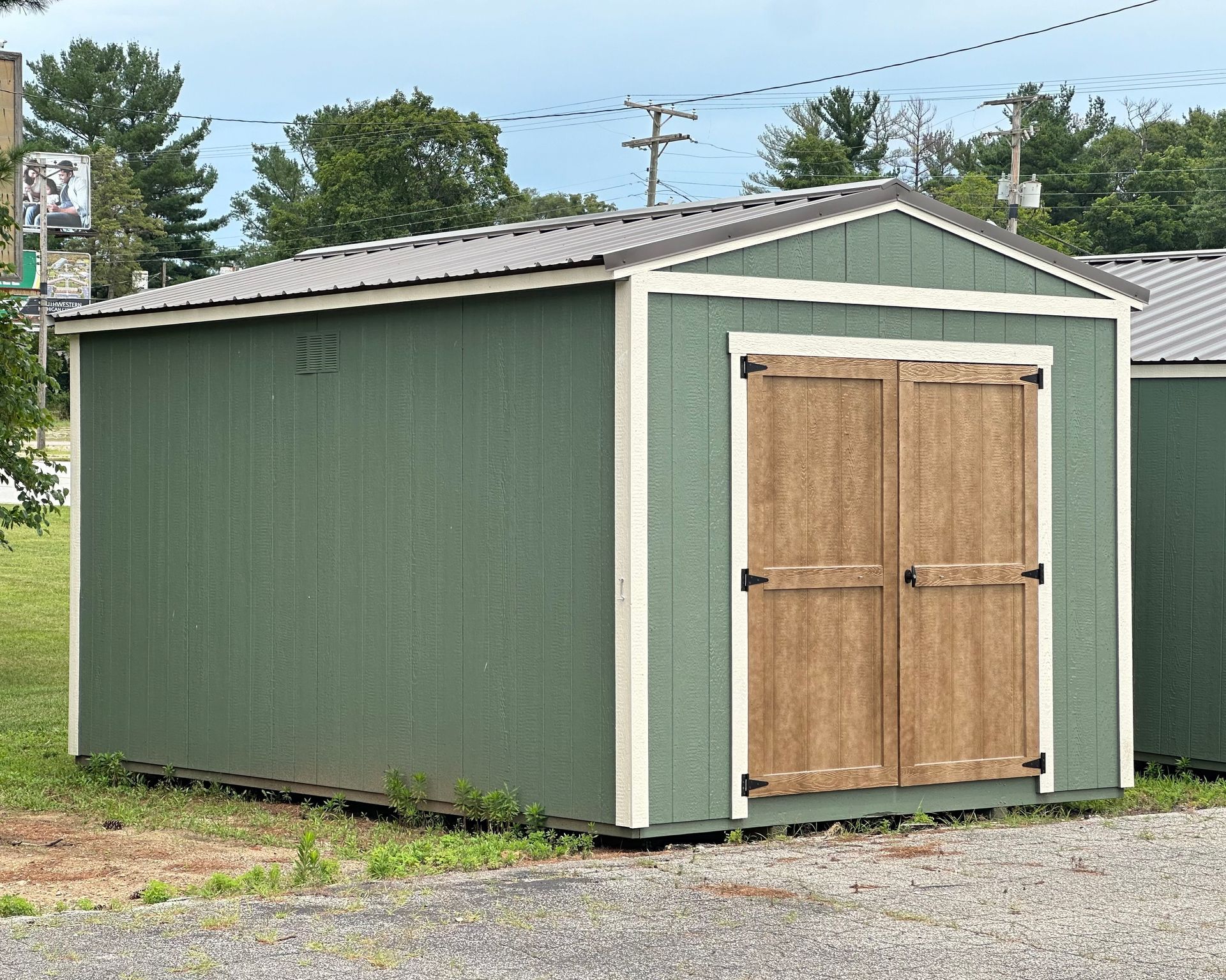 A green shed with a wooden door and a metal roof