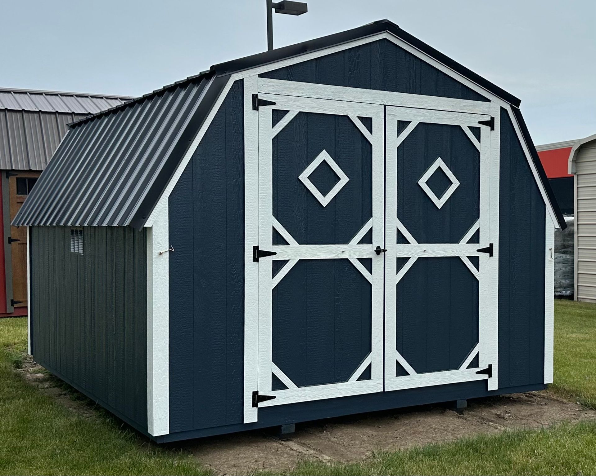 A blue and white barn shed is sitting in the grass.