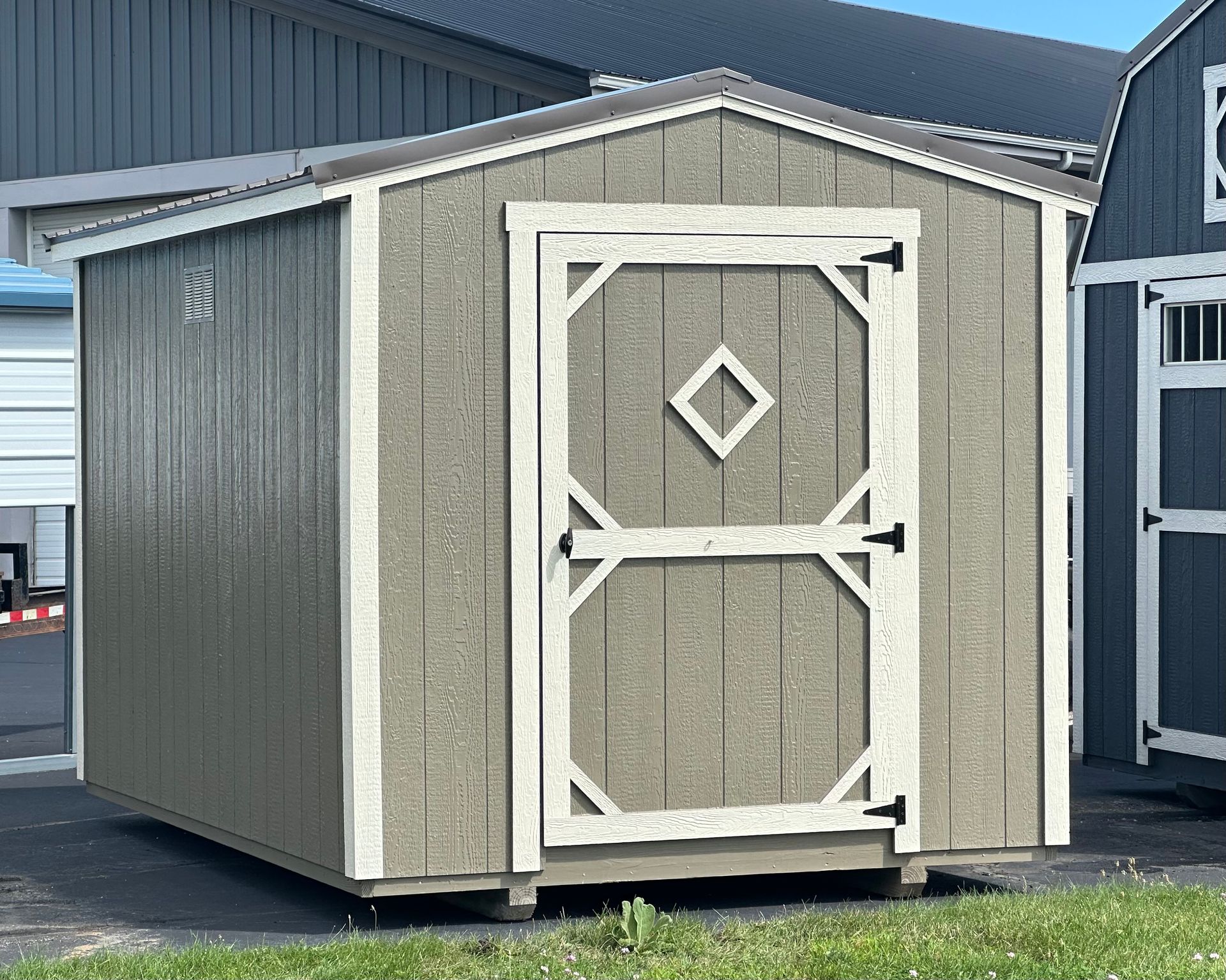 A small shed with a diamond on the door is sitting in the grass.