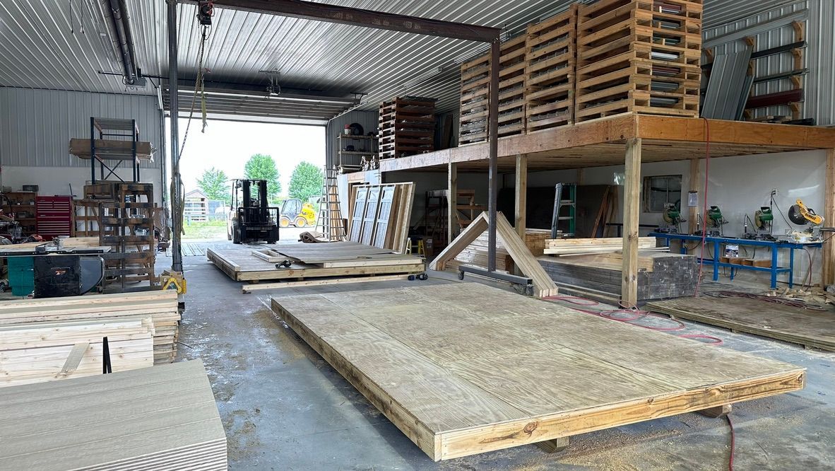 A large warehouse filled with wooden pallets and a forklift.