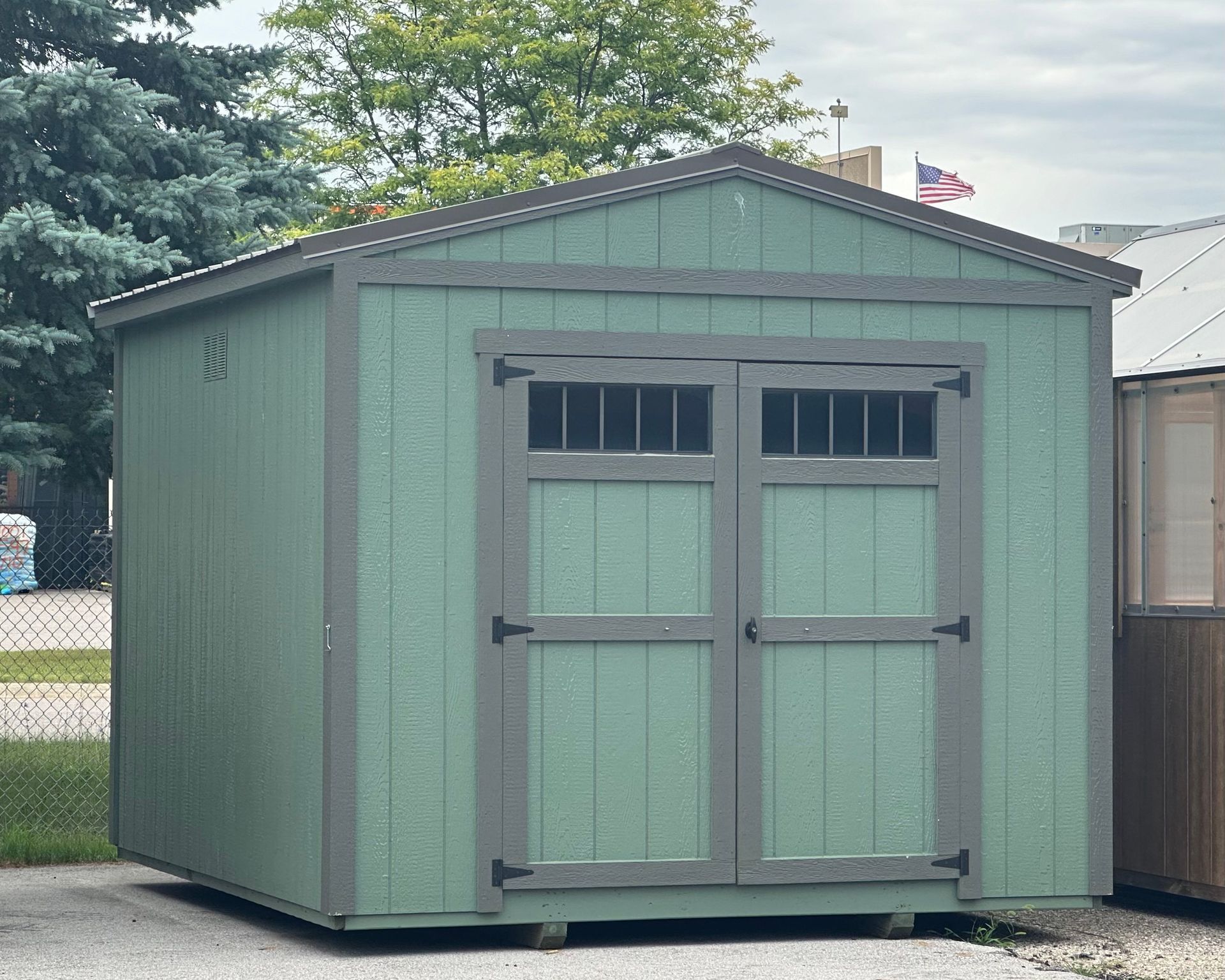 A green shed with gray trim and a window