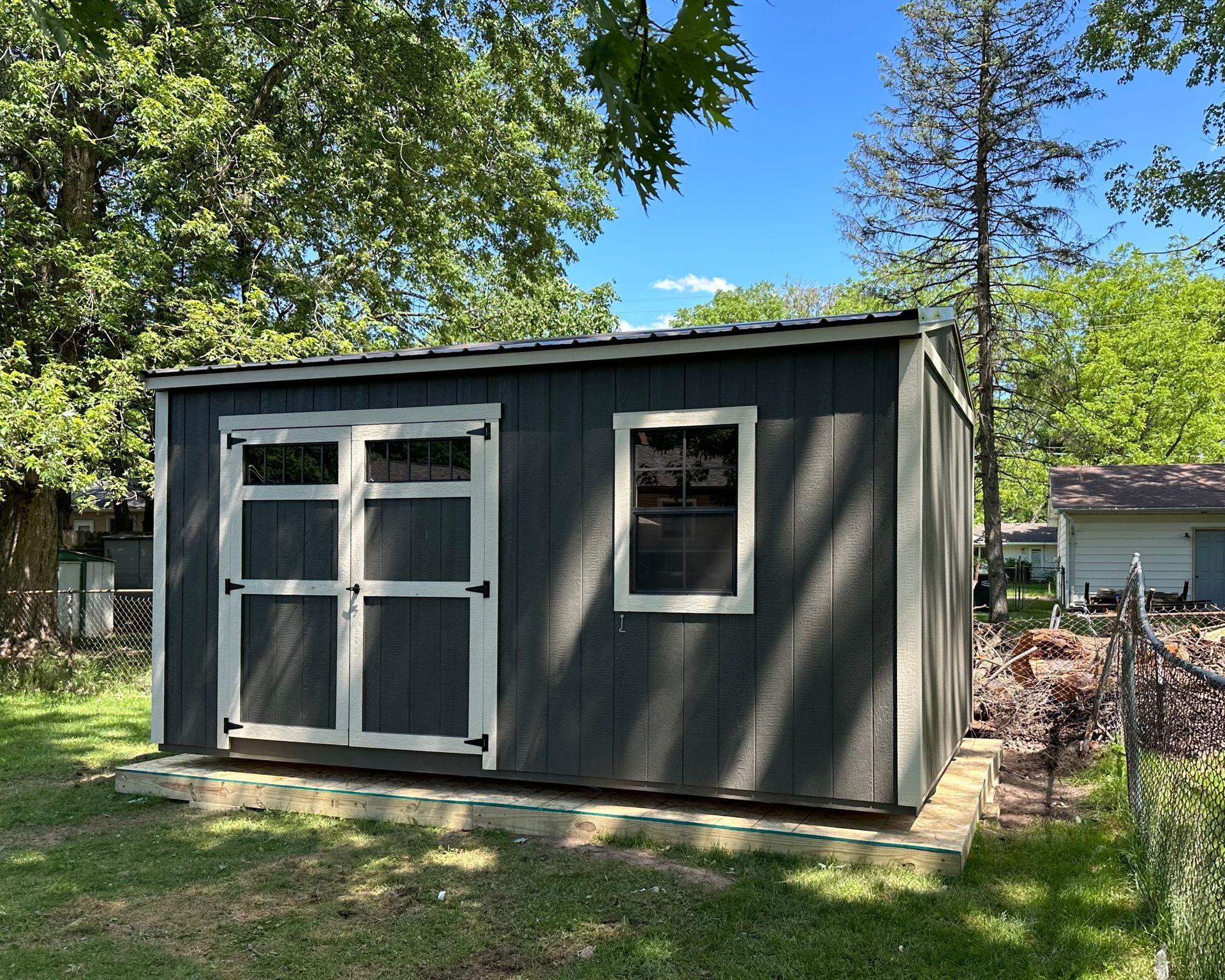 A small shed with a window and a fence in front of it.
