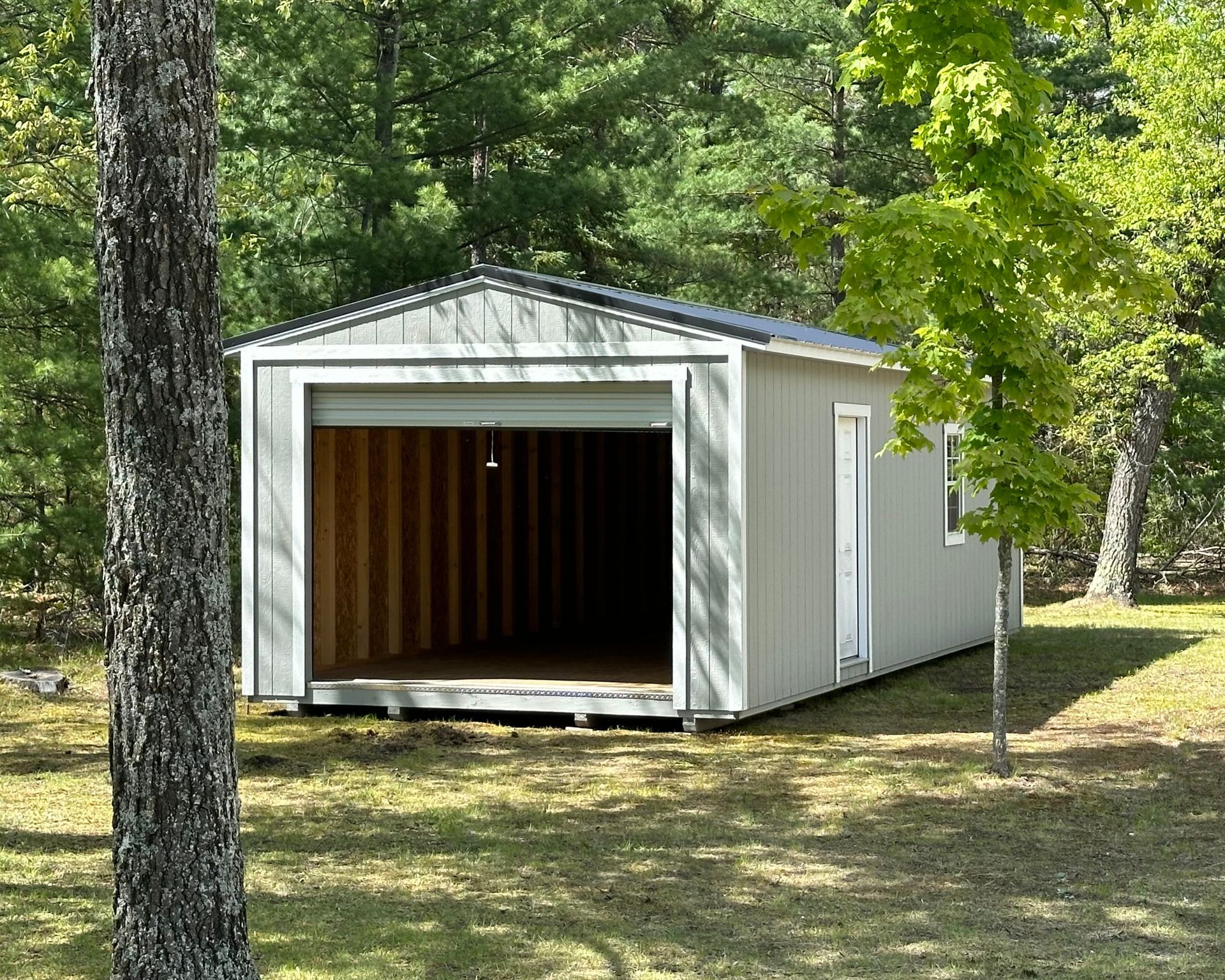 A garage with the door open and trees in the background