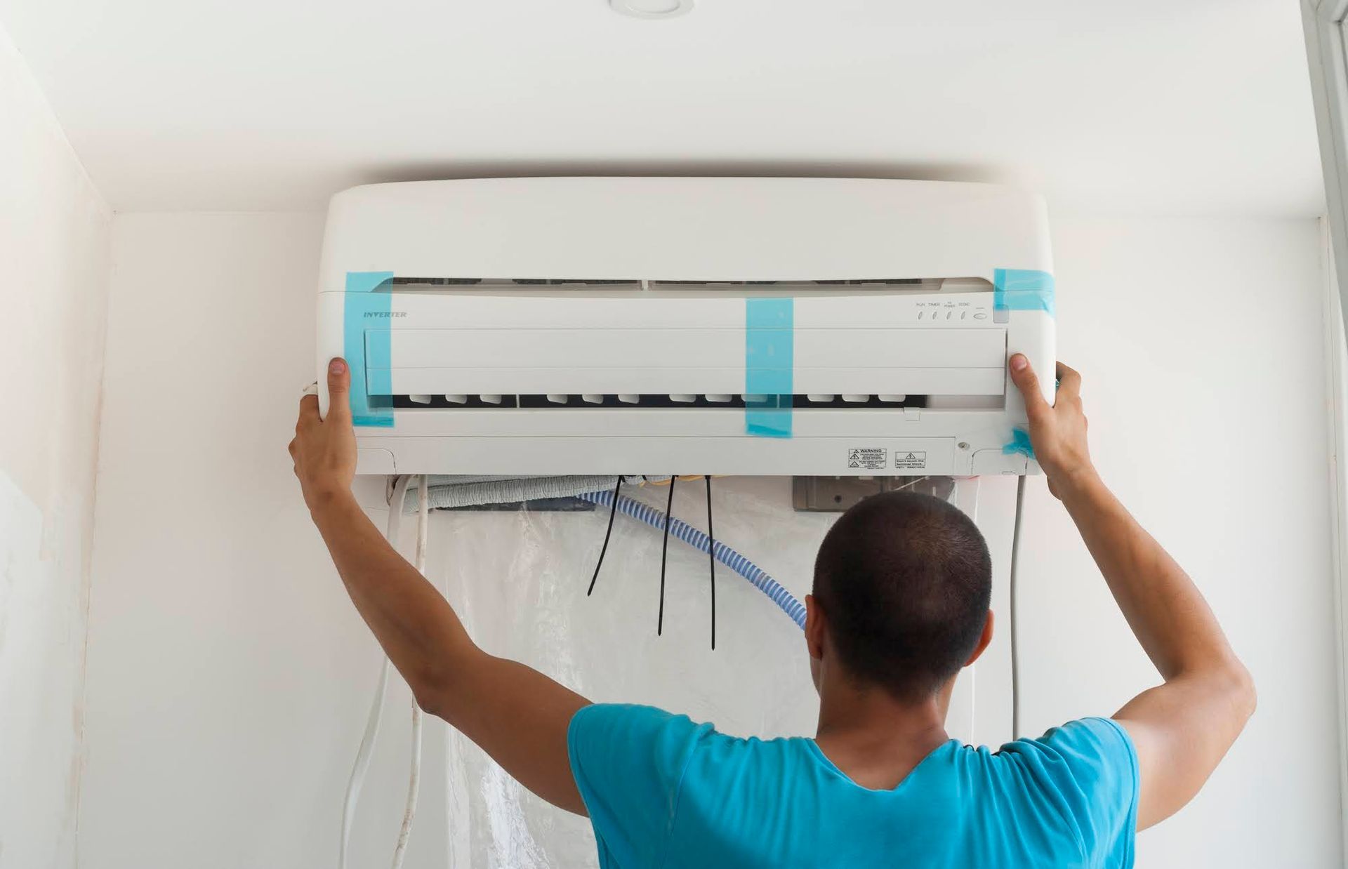 A Man Is Installing an Air Conditioner on A Wall.