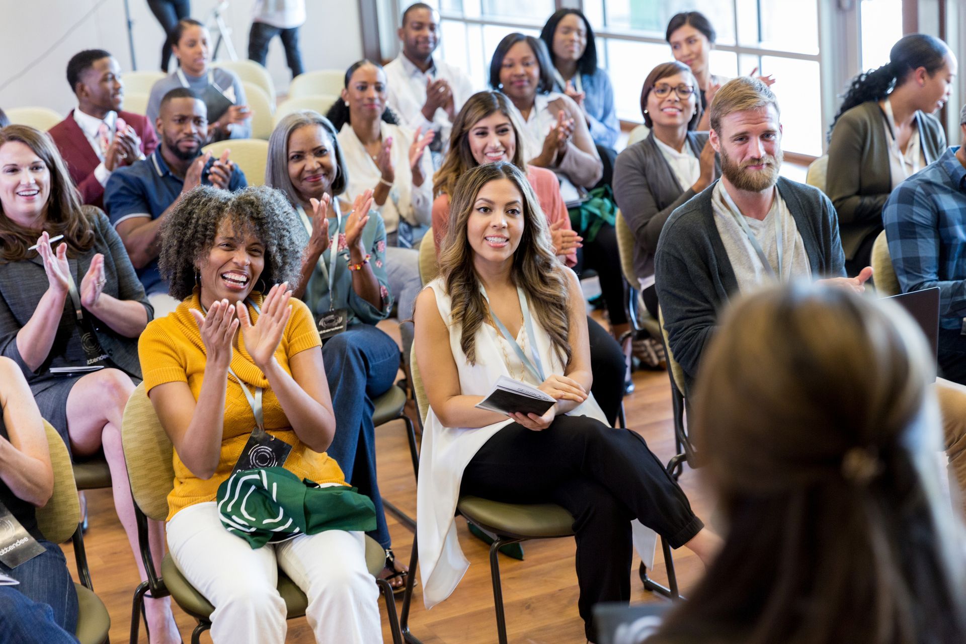 Un gruppo di persone è seduto su delle sedie e applaude durante una presentazione.