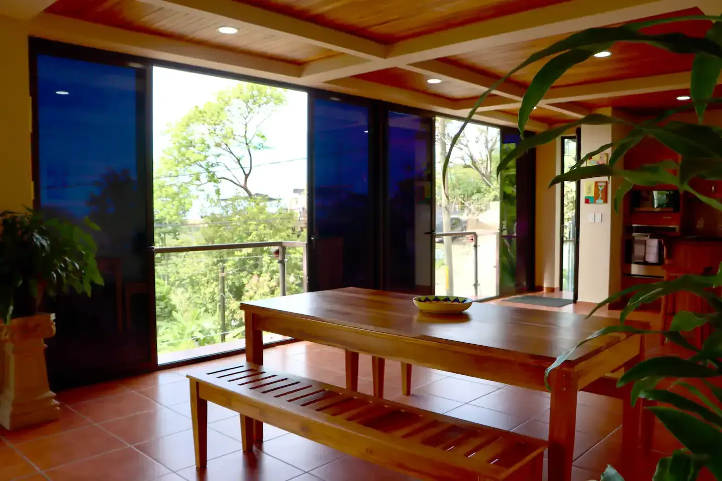 A wooden table with a bench in a room with lots of windows