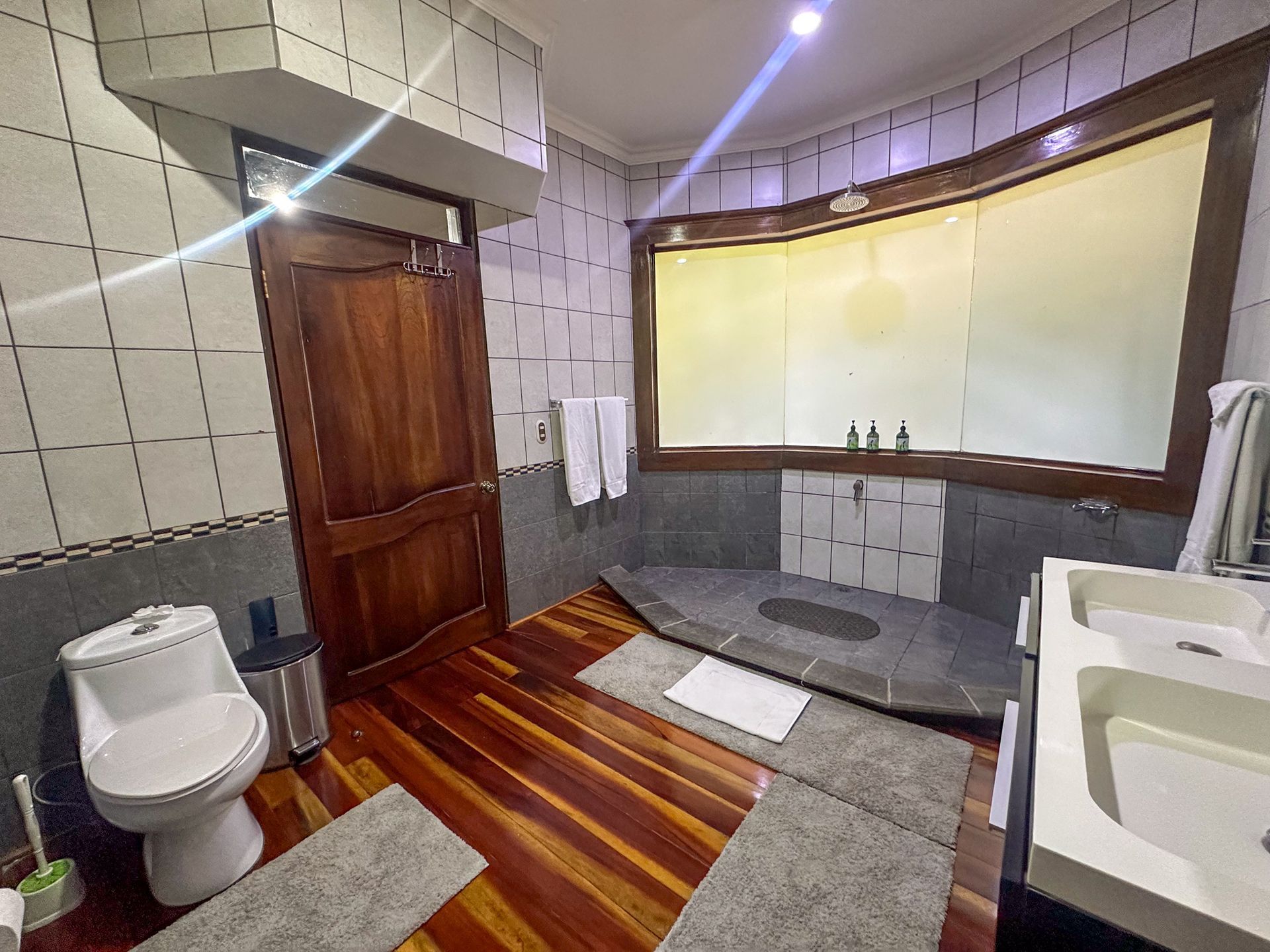 A bathroom with a toilet , sink , and large window.