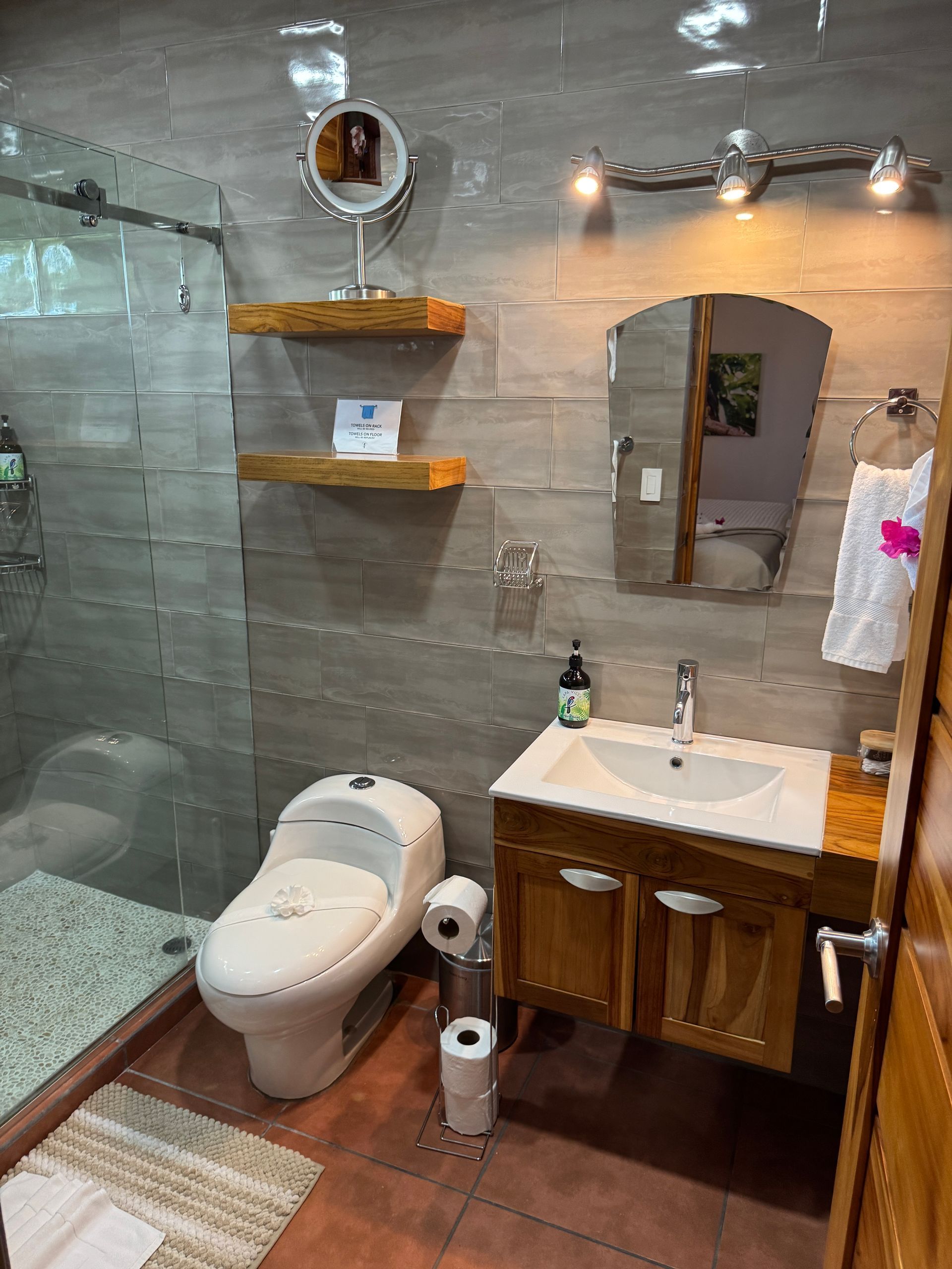 A bathroom with a toilet , sink , mirror and shower.