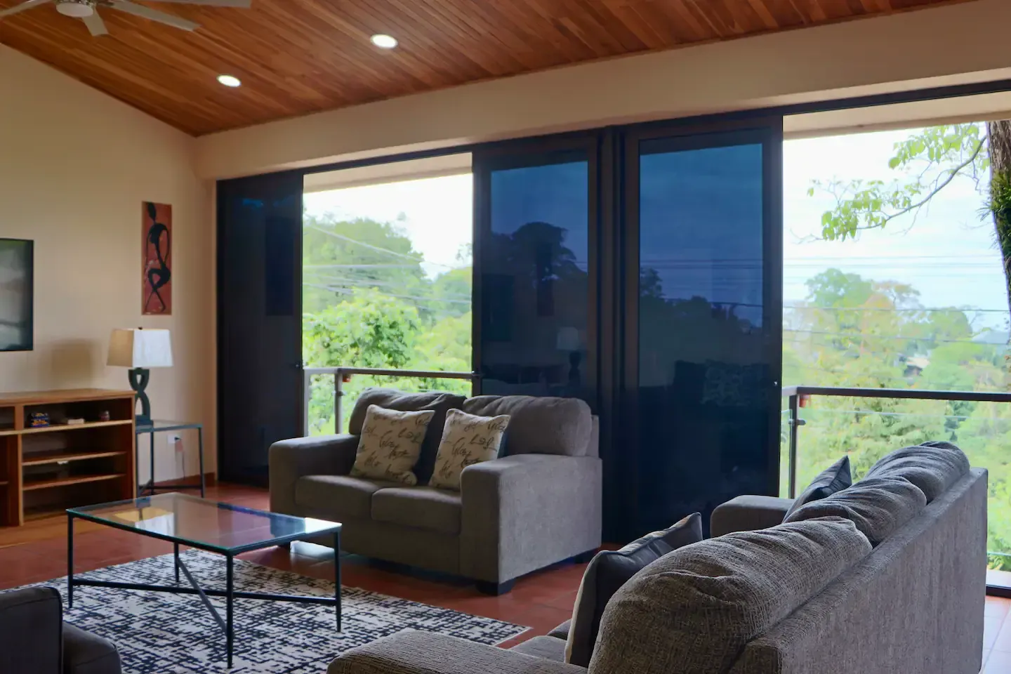 A living room with a couch , chair , coffee table and sliding glass doors.
