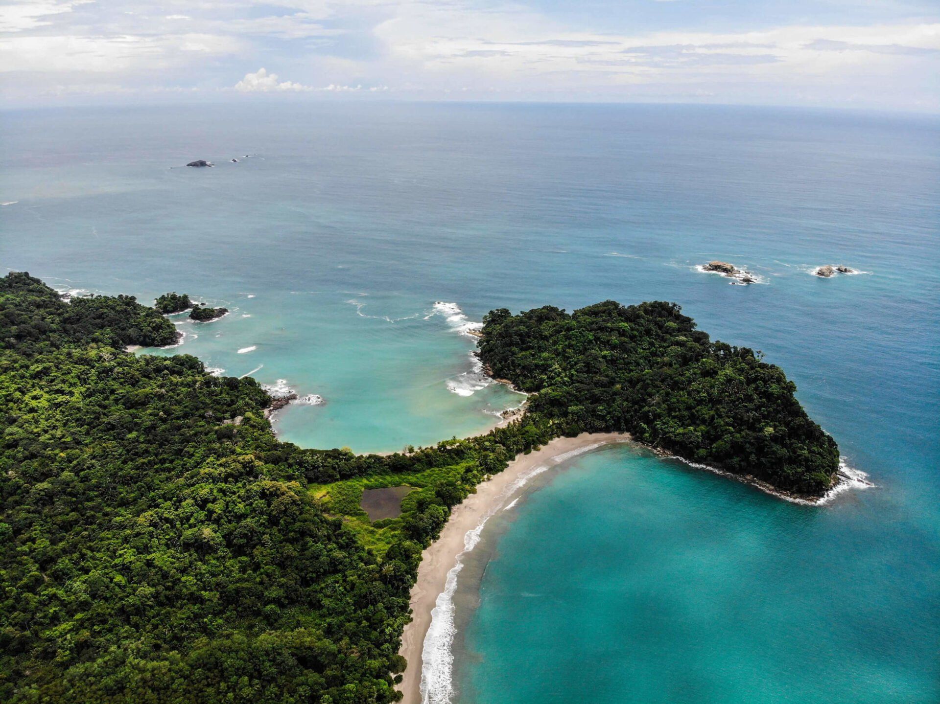 An aerial view of a small island in the middle of the ocean surrounded by trees.
