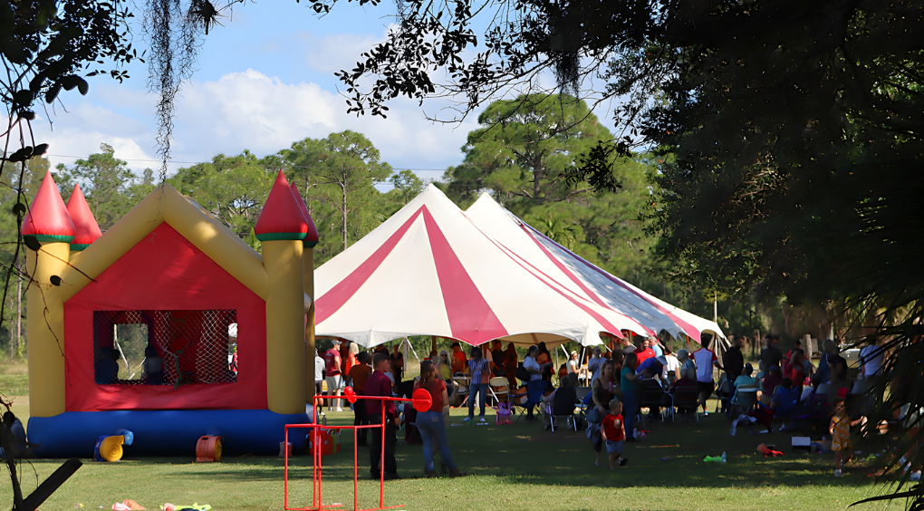 Group of students and adults outdoors, wearing matching gray t-shirts, posing in front of trees.