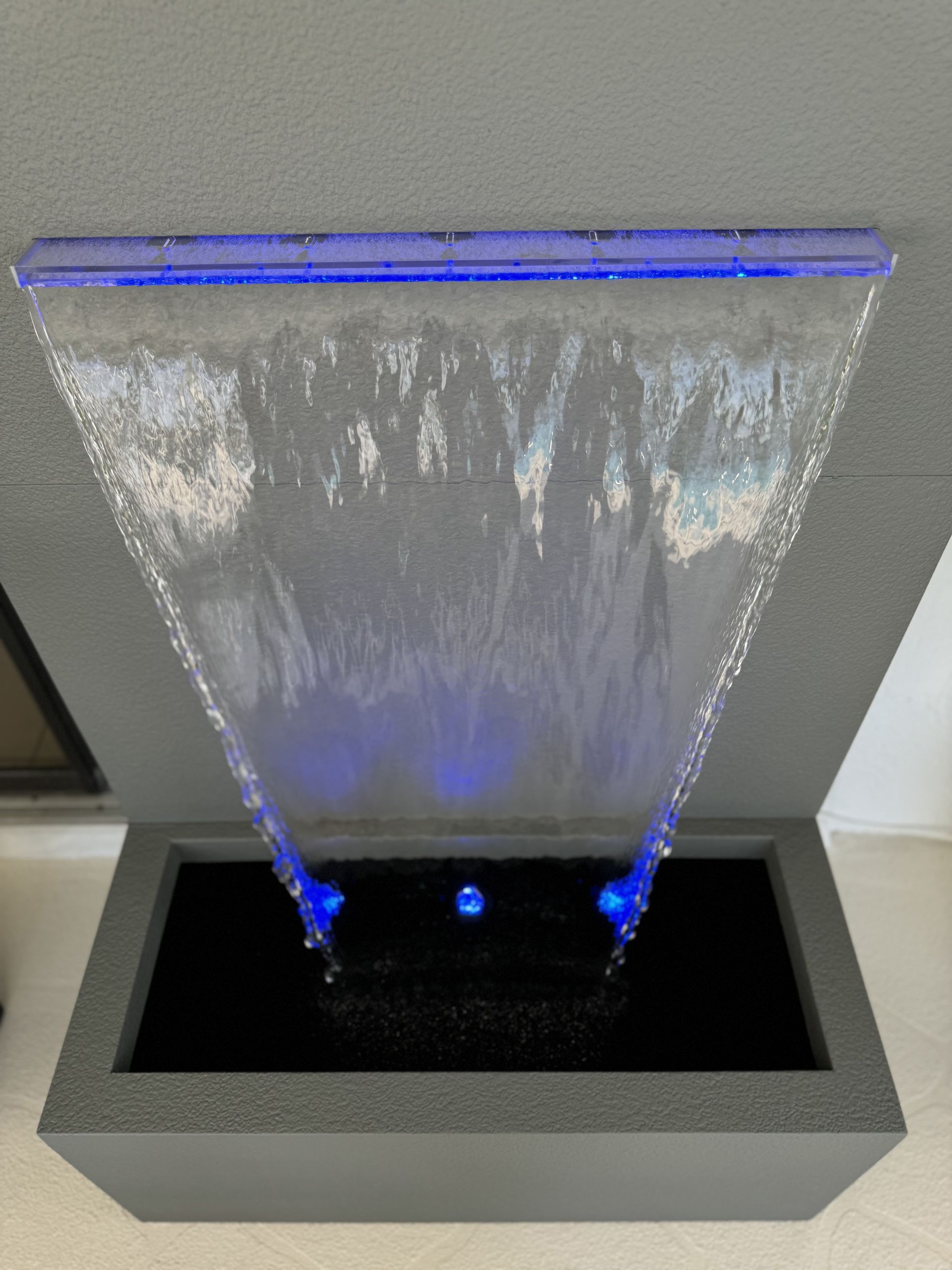 Water fountain with blue LED lights flowing down a triangular shape