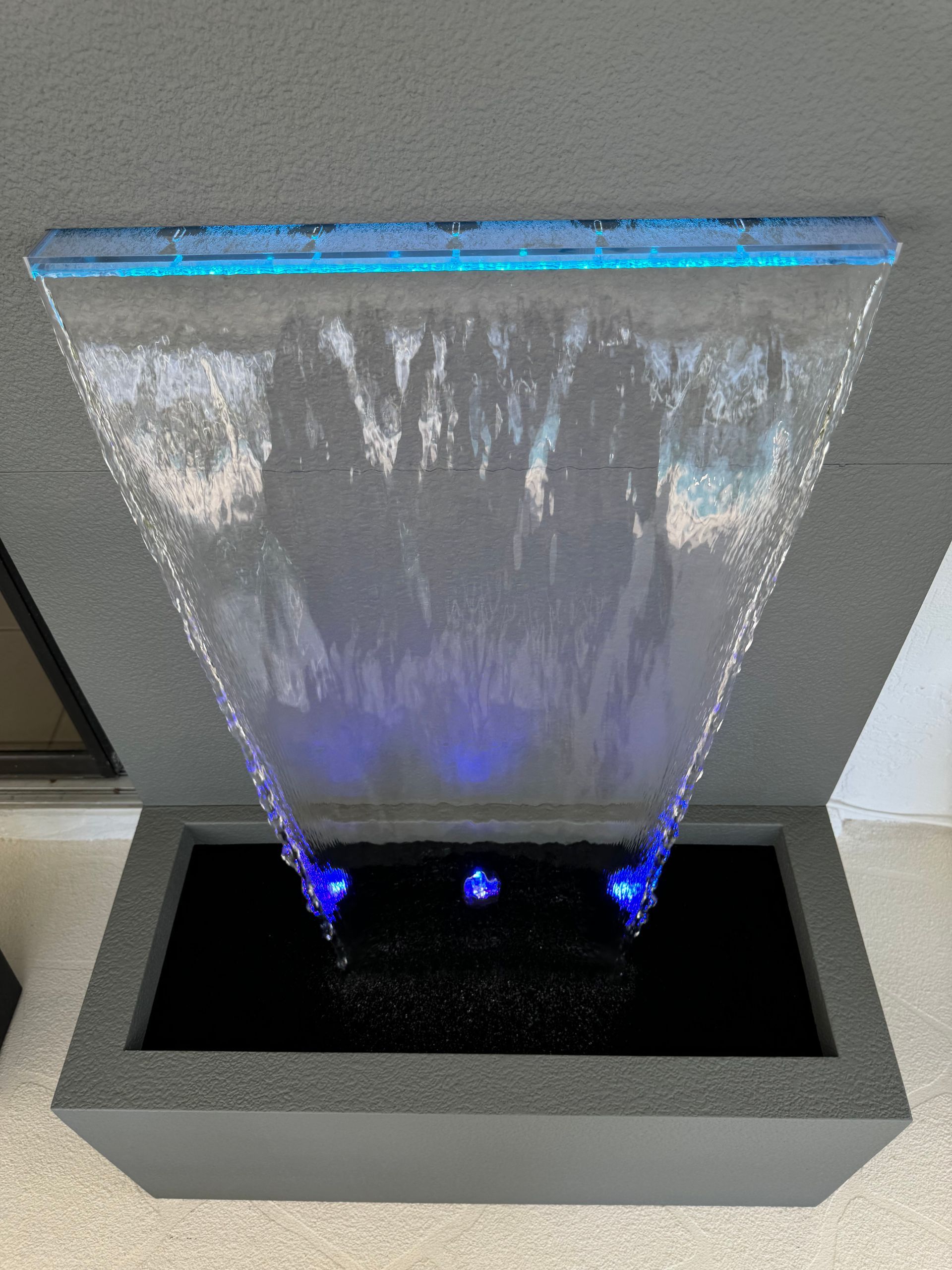 Water fountain with blue LED lights cascading into a dark basin