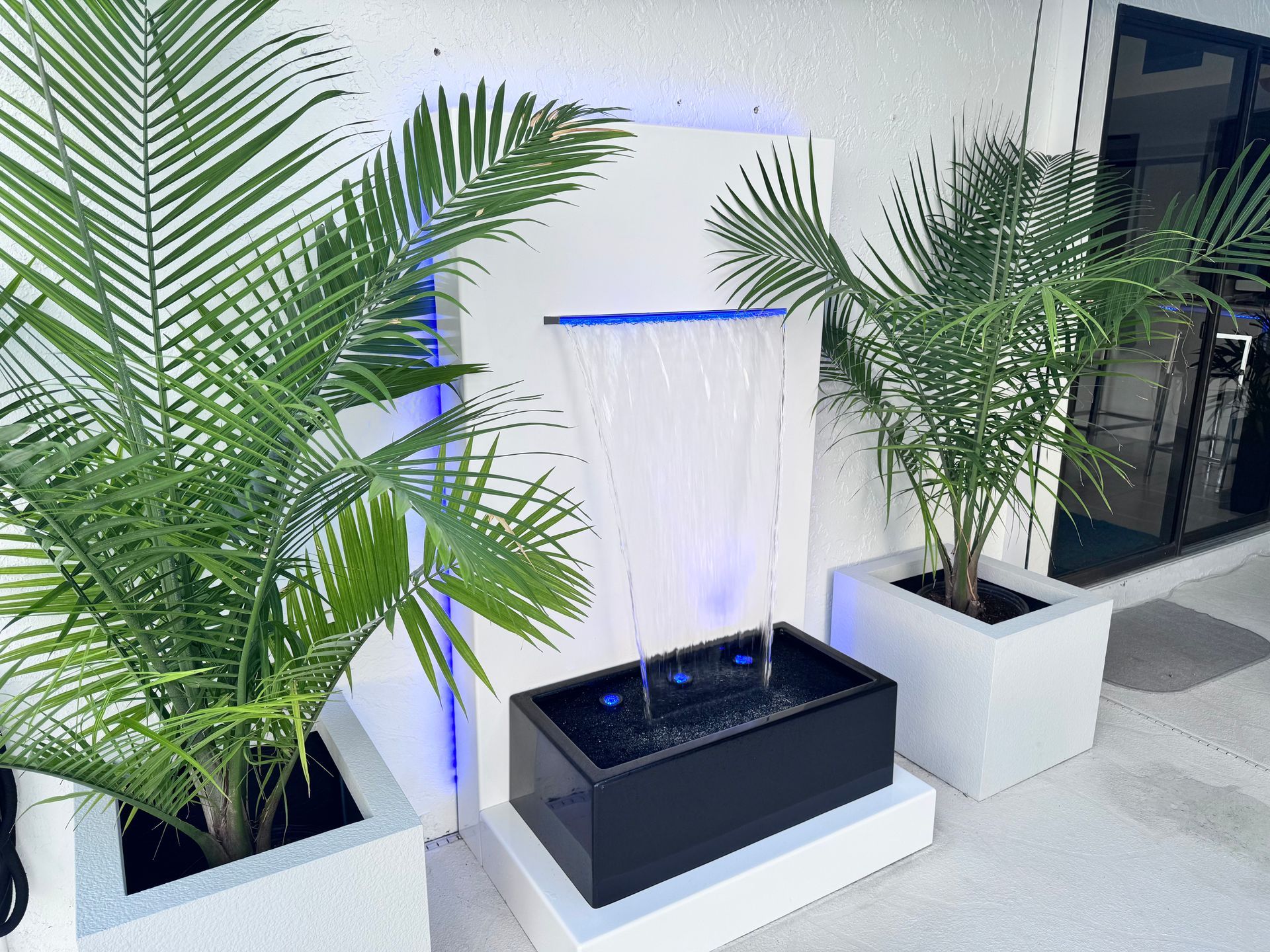 Water fountain with palm trees in white planters