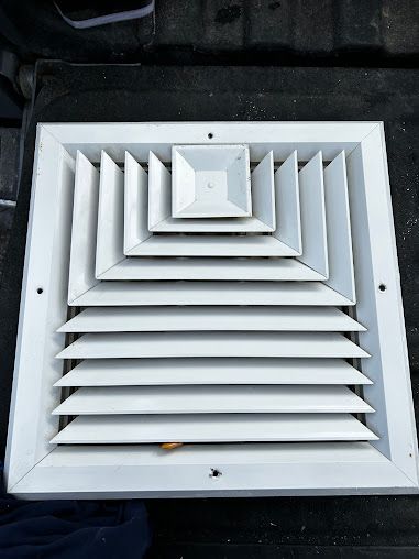 A white air vent is sitting on top of a black table.
