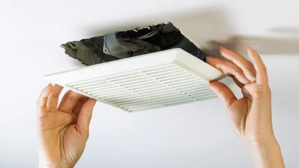 A person is fixing a ceiling fan with their hands.