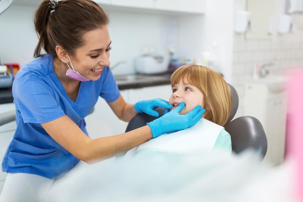 A Little Girl Is Sitting in A Dental Chair While a Dentist Examines Her Teeth — Steve King Dental Group in Edmonton, QLD