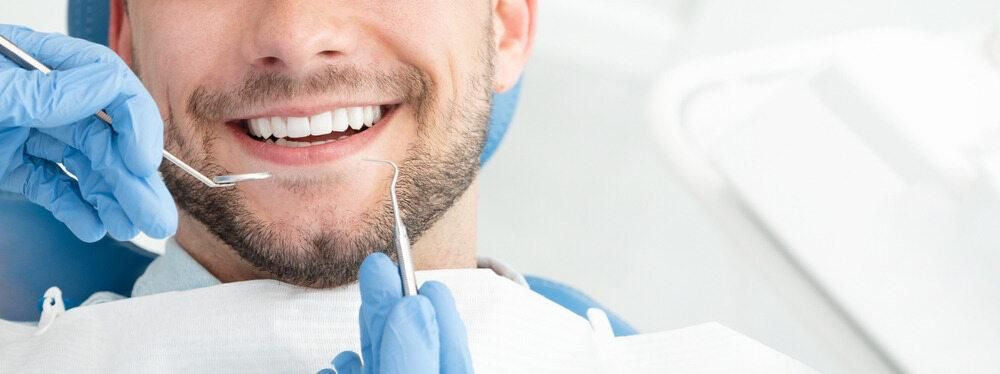 A Man Is Having His Teeth Examined by A Dentist — Steve King Dental Group in Manunda, QLD