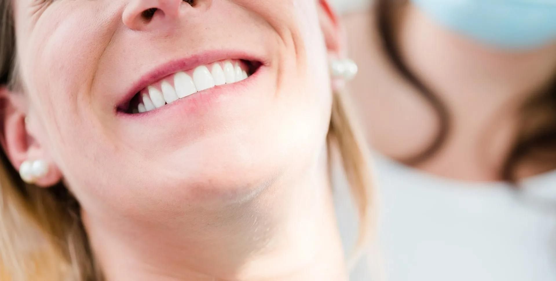 A Woman Is Smiling While Sitting in A Dental Chair — Steve King Dental Group in Manunda, QLD