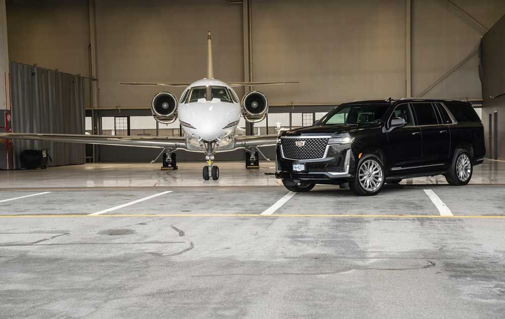 Black SUV parked in front of a private jet inside a hangar.