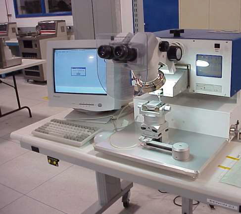 A white, bench-mounted microscope workstation with a computer monitor and keyboard in a laboratory setting.