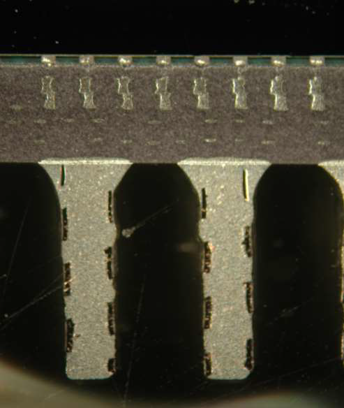 A microscopic cross-section showing solder joints between a dark electronic component and a metallic circuit board base.
